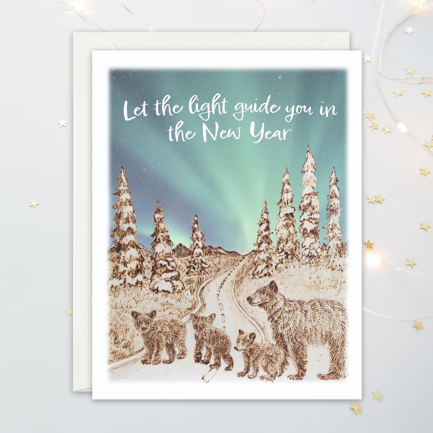 Greeting card illustration with four bears  on a winding path, snowy landscape, Northern Lights and text 'Let the light guide you in the New Year'