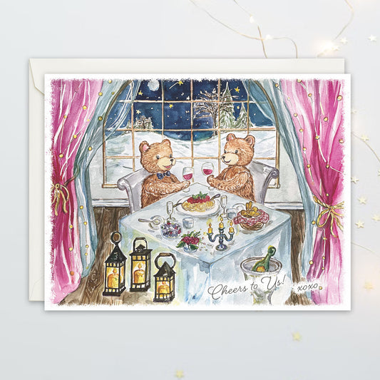 Greeting card with two bears at a dinner table in a window, surrounded by lanterns and a snowy scene outside.