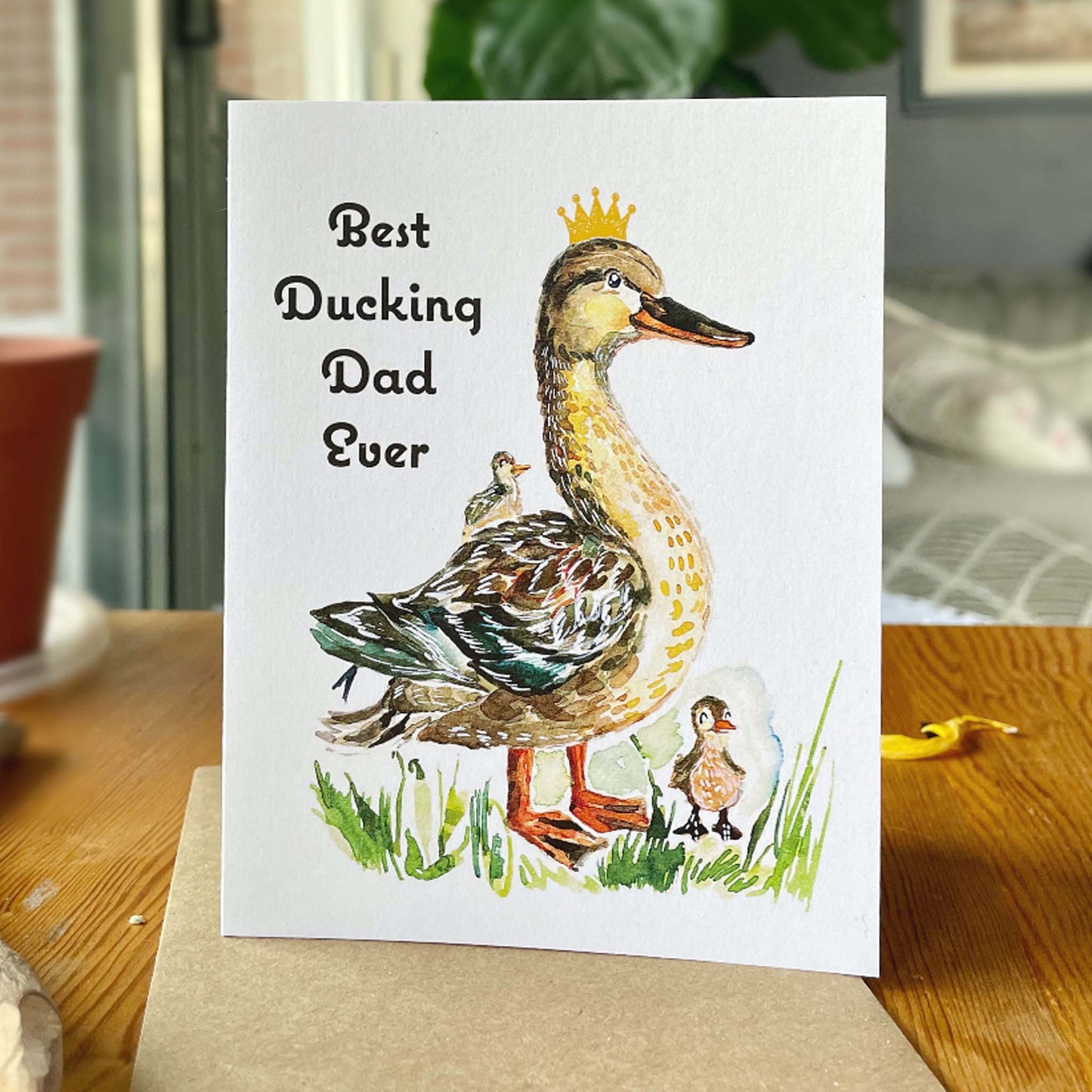 Greeting card with a duck illustration and text 'Best Ducking Dad Ever' on a wooden surface.