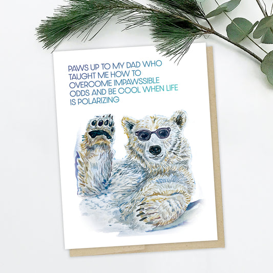 A picture of a polar bear card. The card is of a polar bear chilling, in Ray Ban style sunglasses. He has one paw raised saluting you. The text reads: Paws up to my dad who taught me how to overcome "impawssible" odds and be cool when life is polarizing.