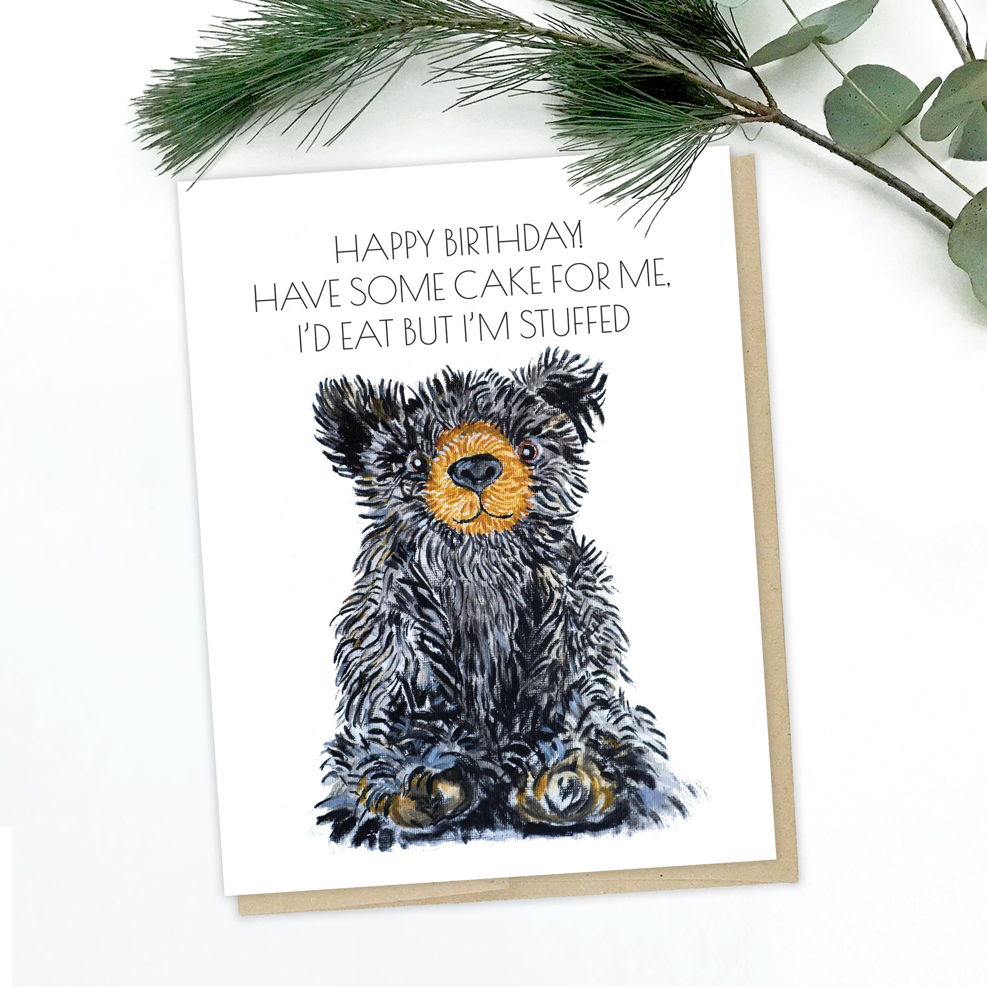 A picture of a teddy bear greeting card. The bear is black with perky ears, a brown snout and brown/white paws. The text reads: happy birthday! have some cake for me. I'd eat but I'm stuffed.